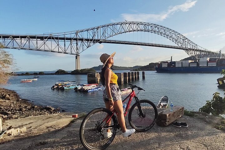 A traveller with a bicycle beside the Bridge of the Americas in Panama